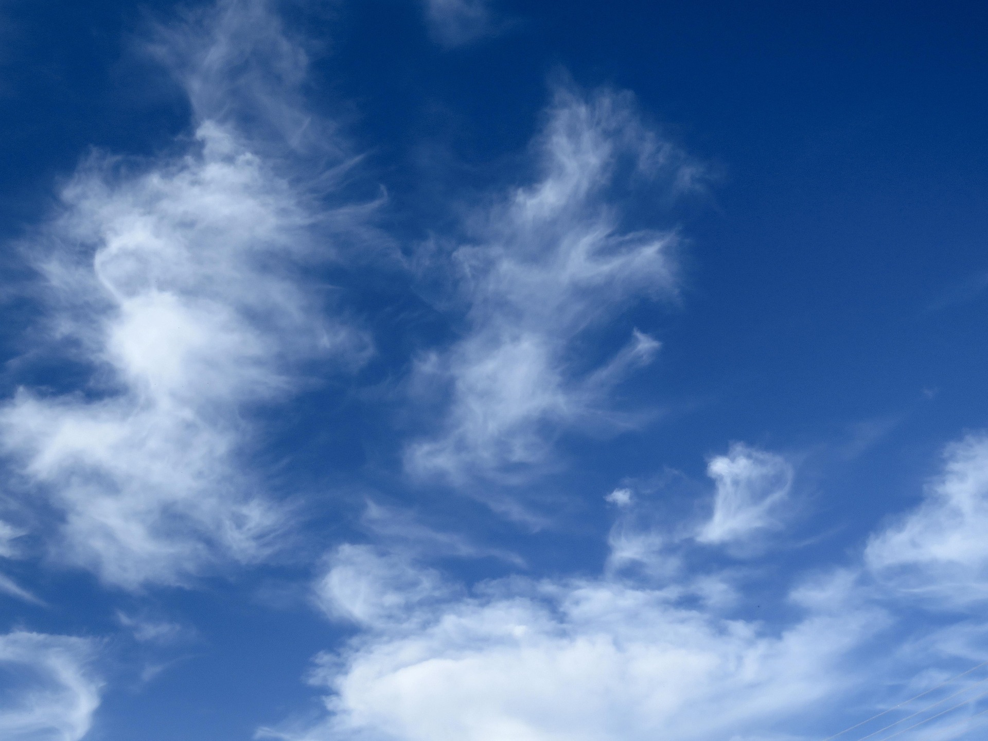 Clear bright blue sky with soft white clouds, atmosphere and sunlight scattering